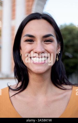 Happy young latin woman smiling outdoors in urban setting Stock Photo