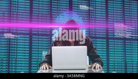 Hacker in hoodie using laptop with digital code and glowing interface Stock Photo