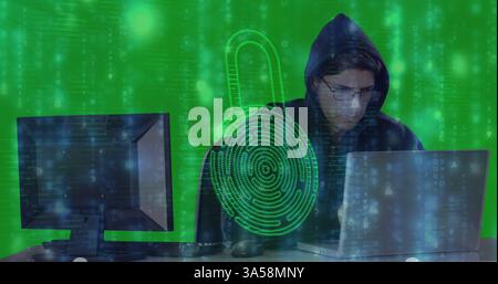 Hooded person using laptop with digital lock overlay, focusing on cybersecurity Stock Photo