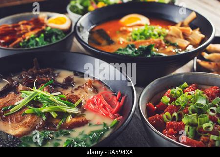 A view of several ramen bowls and assorted Asian appetizers on a restaurant table. Stock Photo
