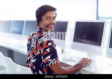 Customer service representative smiling while using headset at computer in office, copy space Stock Photo