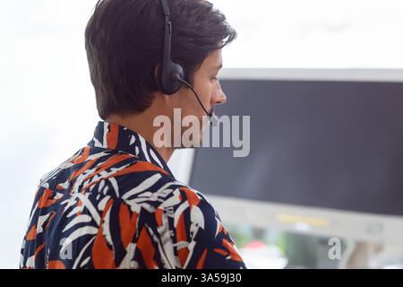 Customer service representative wearing headset assisting clients at office desk, copy space Stock Photo