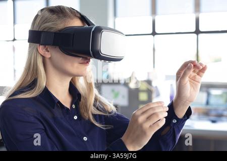 Woman using VR headset in modern office, interacting with virtual objects Stock Photo