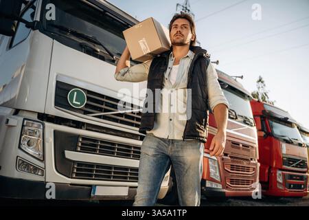 Delivery is on the way, with box. Truck driver is near the transport outdoors. Stock Photo