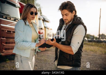 Truck driver is with woman, doing business, holding notepad, documents. Stock Photo