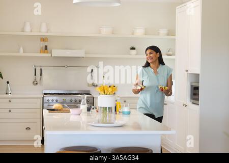 Smiling woman preparing healthy snacks in modern kitchen, enjoying family time, copy space Stock Photo