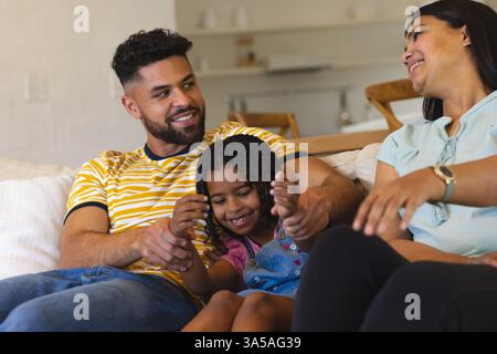 Happy family relaxing on couch, parents playing with daughter at home Stock Photo