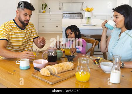 Family enjoying breakfast together at home, sharing juice and pastries Stock Photo