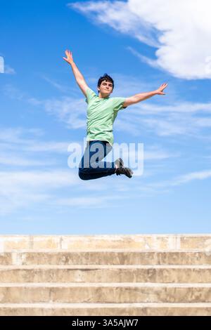 Energetic young man jumping with joy against a clear blue sky Stock Photo