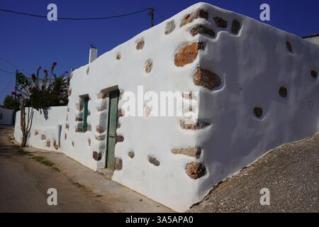 A house with a bright whitewashed exterior in a village contrasts with natural stones embedded around the corners and randomly place on the walls. Stock Photo