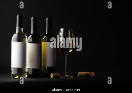 Tasty wine in glass, bottles and corks on black background, space for text Stock Photo
