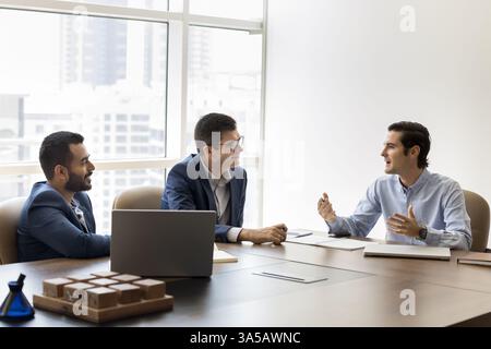 Three professionals engaged in discussion seated at conference table Stock Photo