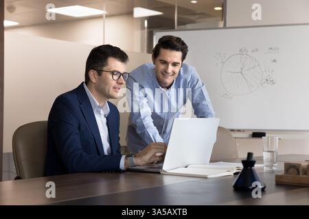 Two business professionals collaborate using laptop during brainstorming session Stock Photo