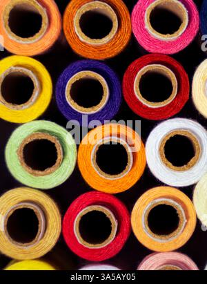 A top-down angle photo of colorful thread reels arranged on a white background. Ideal for crafting blogs, sewing tutorials, and creative projects. Stock Photo