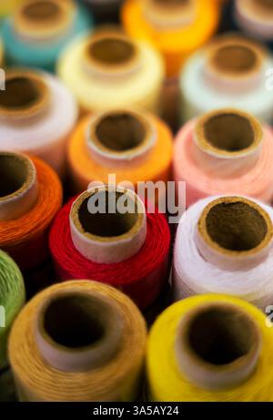 A detailed close-up shot of colorful thread reels, placed alongside a reel, on a white background. Ideal for emphasizing details in crafting or sewing Stock Photo