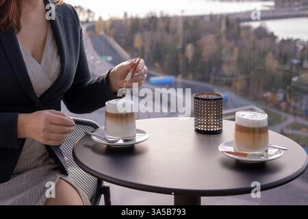 Young woman drinking coffee in a cafe on the background of the city Stock Photo