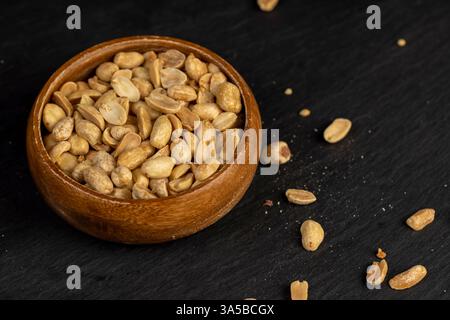 fried peeled peanut kernels in a wooden bowl, fried yellow peanuts with a little salt on the table Stock Photo