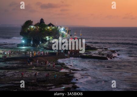 Bali, Indonesia, 10 Oct 2024 Immerse yourself in the breathtaking beauty of the sunset at Tanah Lot Temple in Bali, where vibrant visitors participate Stock Photo