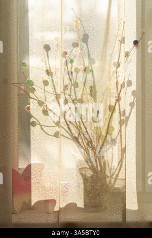 Easter decoration on a windowsill with soft sunlight shining through sheer curtains Stock Photo