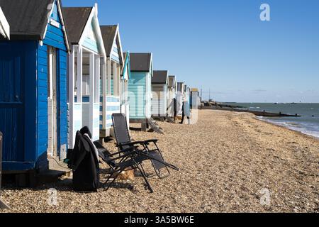 Beach owner went to visit their neighbours with deck chairs left behind in front of beach huts , Southend-on-Sea , Essex England UK Stock Photo