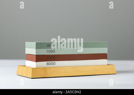 grey background on table lies red and green equipment a set for sharpening and polishing kitchen knives and various blades different abrasiveness of Stock Photo
