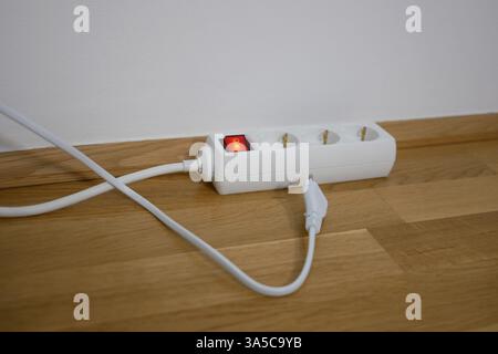 The electric cable is lying next to power strip socket extension cord. Stock Photo