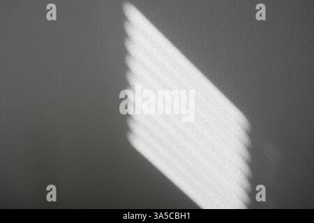 Reflection of light from blinds on white wall. Contrast of light and shadow. Stock Photo
