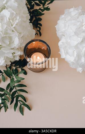 White hydrangea flowers with candles on a beige background. Romantic,Beautiful pastel hydrangea flower background with space for text. Stock Photo