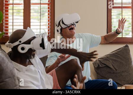 Seniors enjoying virtual reality experience, laughing and interacting at home Stock Photo