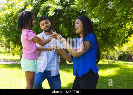 Family enjoying playful moment outdoors, smiling and bonding under sunny trees Stock Photo