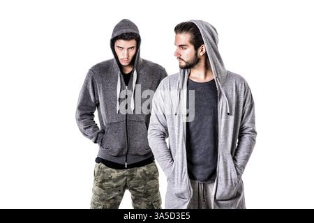 Two young men wearing military and sport clothes. Wearing hoods on heads. Studio shot Stock Photo