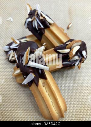 Freshly made cookies are decorated with rich chocolate and topped with shredded coconut on a baking sheet, ready to be served. Stock Photo