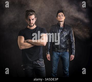 Two attractive young hard rock men posing in studio. Black background Stock Photo
