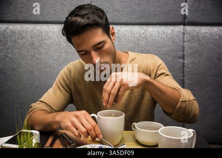 Attractive Young Man Eating Breakfast, Having some Cereal with Milk or Cappuccino Stock Photo