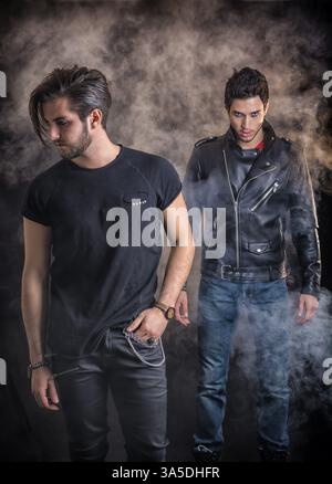 Two attractive young hard rock men posing in studio. Black background Stock Photo