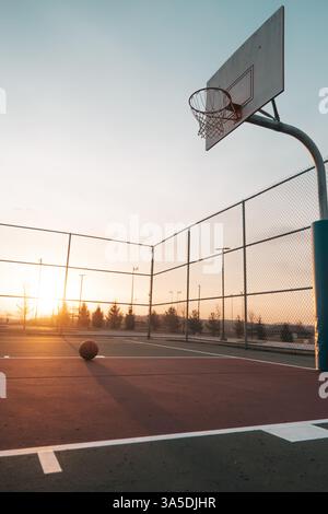 Basketball court at sunset with a single ball on the ground Stock Photo