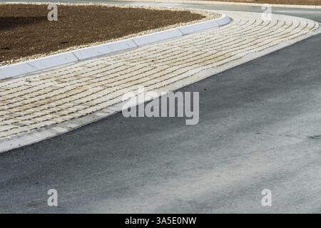Tactile paving guides pedestrians, connecting asphalt road and concrete curb near a soil patch, Bottrop, NRW, Germany, Europe Stock Photo