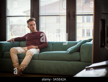 Young man sitting watching television changing the channel with the remote control Stock Photo