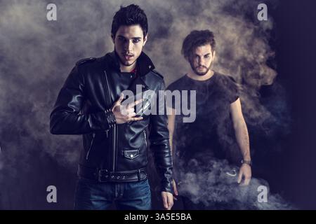 Two attractive young hard rock men posing in studio. Black background Stock Photo