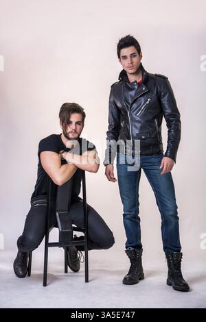 Two attractive young hard rock men posing in studio. Black background Stock Photo