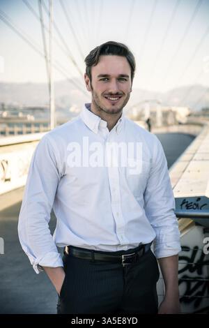 Handsome young man outside wearing white shirt, looking at camera, day shot Stock Photo