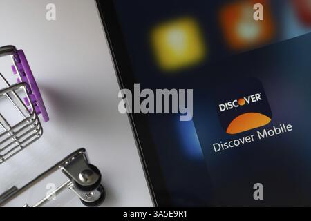 A close up of an iPad screen displaying the Discover Mobile app alongside a mini shopping cart Stock Photo