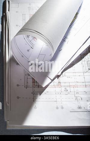 Blueprints on architect desk. Stacked and rolled up architectural projects on natural window light. Construction and building concept Stock Photo