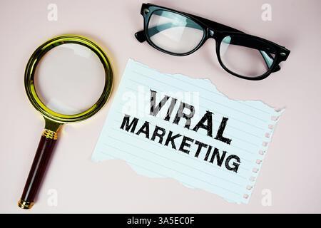 Viral Marketing text written on paper with eyeglasses and magnifying glass flat lay on pink background Stock Photo