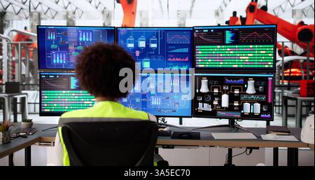 Young African American engineer operates Scada system at manufacturing plant. Stock Photo