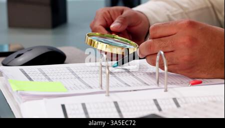 African auditor investigates fraud using magnifying glass in office space. Stock Photo