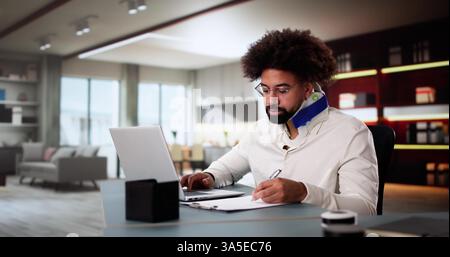 Photo Title: Young Black Man Working From Home With a Broken Arm Stock Photo