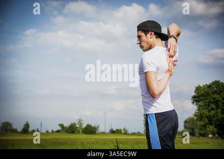 Athletic, handsome fit young man outdoor in country doing stretching exercises Stock Photo