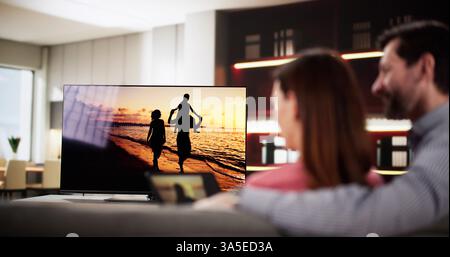 Man streaming video from tablet to television in cozy living room. , interior designer, marketing automation specialist Stock Photo