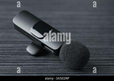 Lavalier microphone on black wooden table, closeup Stock Photo